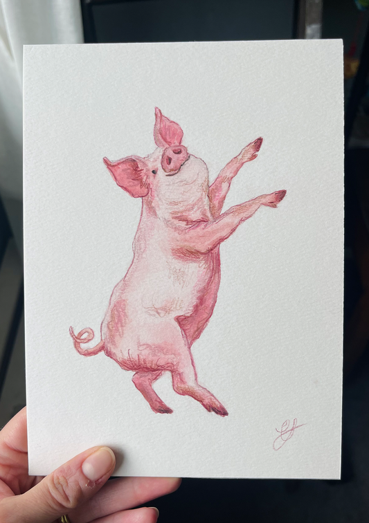 Artist holding a watercolour original painting of a pig dancing the piece is titled Party Pig