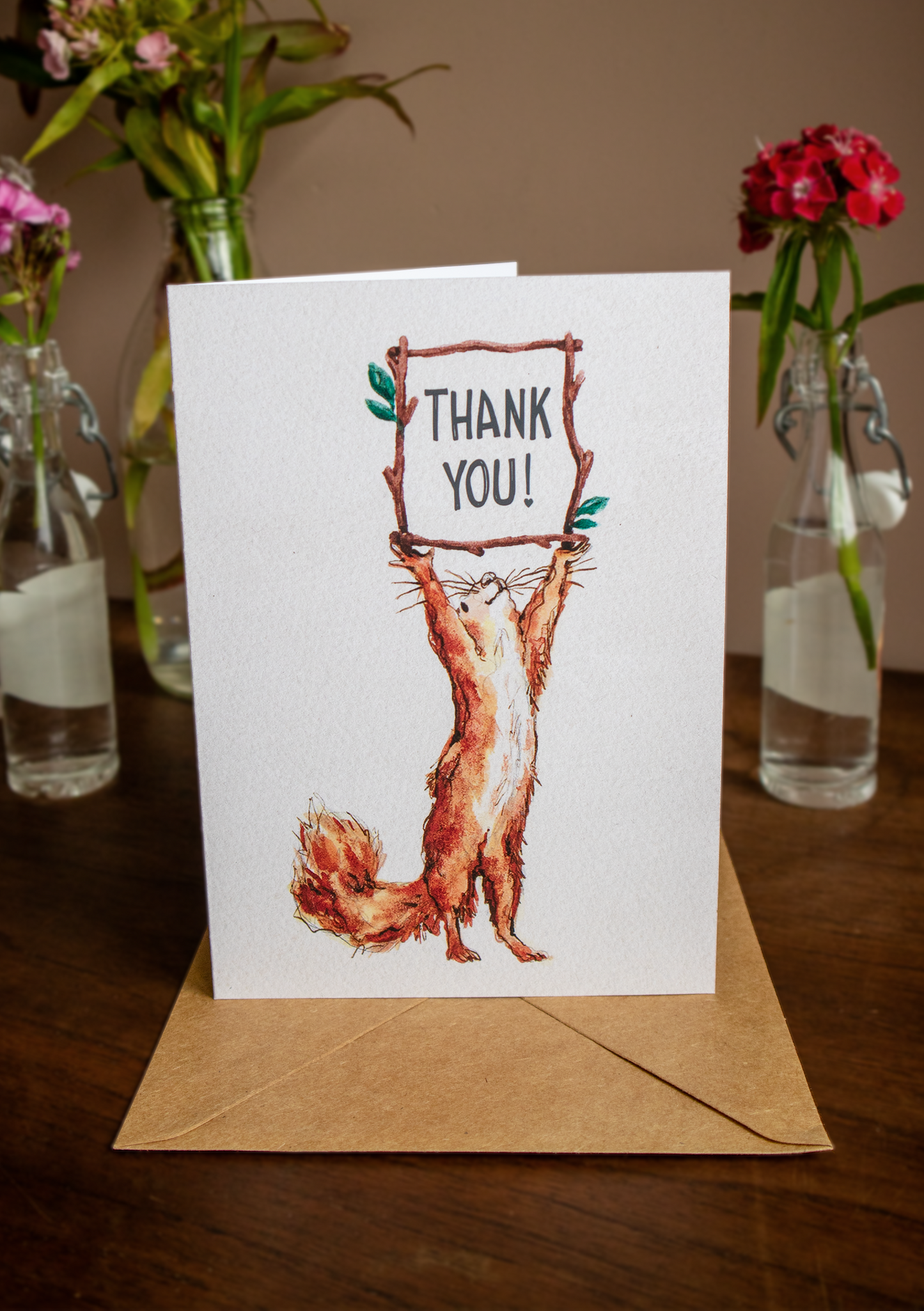 a photo of a thank you card with a squirrel watercolour illustration on and a kraft envelope